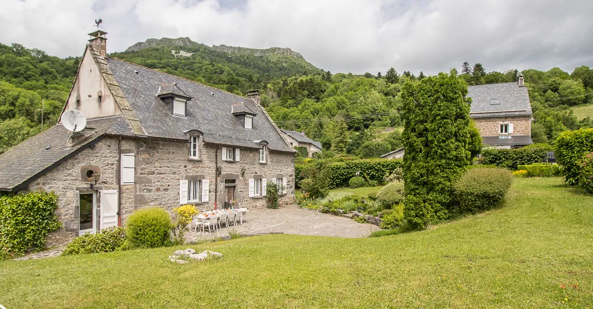 La Closerie de Manou en été — demeure de pierre du XVIIIᵉ siècle et son jardin fleuri, au cœur du Massif du Sancy